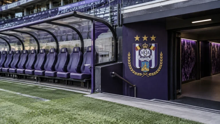 Lege dug-out van RSC Anderlecht met een clubembleem op de wand naast de tunnel.