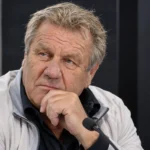 Johan Boskamp in een neutrale voetbalmediaomgeving met een discreet Anderlecht-embleem op de achtergrond.