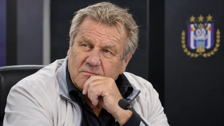 Johan Boskamp in een neutrale voetbalmediaomgeving met een discreet Anderlecht-embleem op de achtergrond.