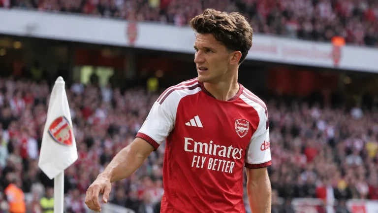 Een voetballer in een rood-wit Arsenal-shirt tijdens een wedstrijdmoment nabij de zijlijn.