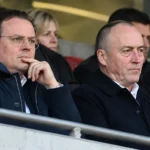 Niet-spelende clubvertegenwoordigers in donkere jassen op de tribune van de Bosuil.