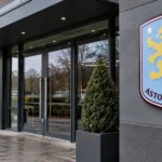 De ingang van een Aston Villa-clubgebouw met het clubembleem op een vaste gevelplaat.