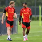 Twee spelers van de Rode Duivels tijdens een training in rode trainingskleding.