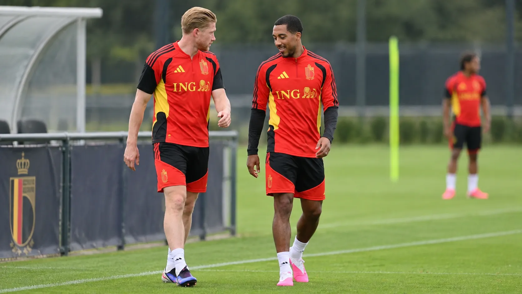 Twee spelers van de Rode Duivels tijdens een training in rode trainingskleding.