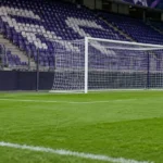 Leeg strafschopgebied met doel en een vast RSC Anderlecht-bord langs het veld.
