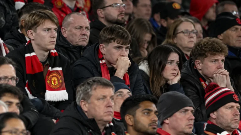 Een groep Manchester United-supporters met sjaals op de tribune van Old Trafford.