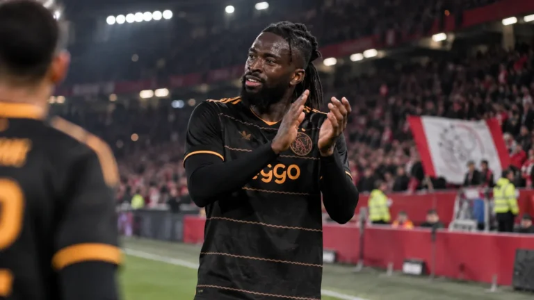Tolu Arokodare applaudisseert in het zwarte Ajax-tenue richting de tribunes.