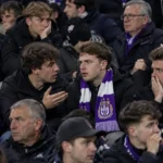 Een groep Anderlecht-supporters reageert in de tribune met een paars-witte sjaal zichtbaar tussen de fans.