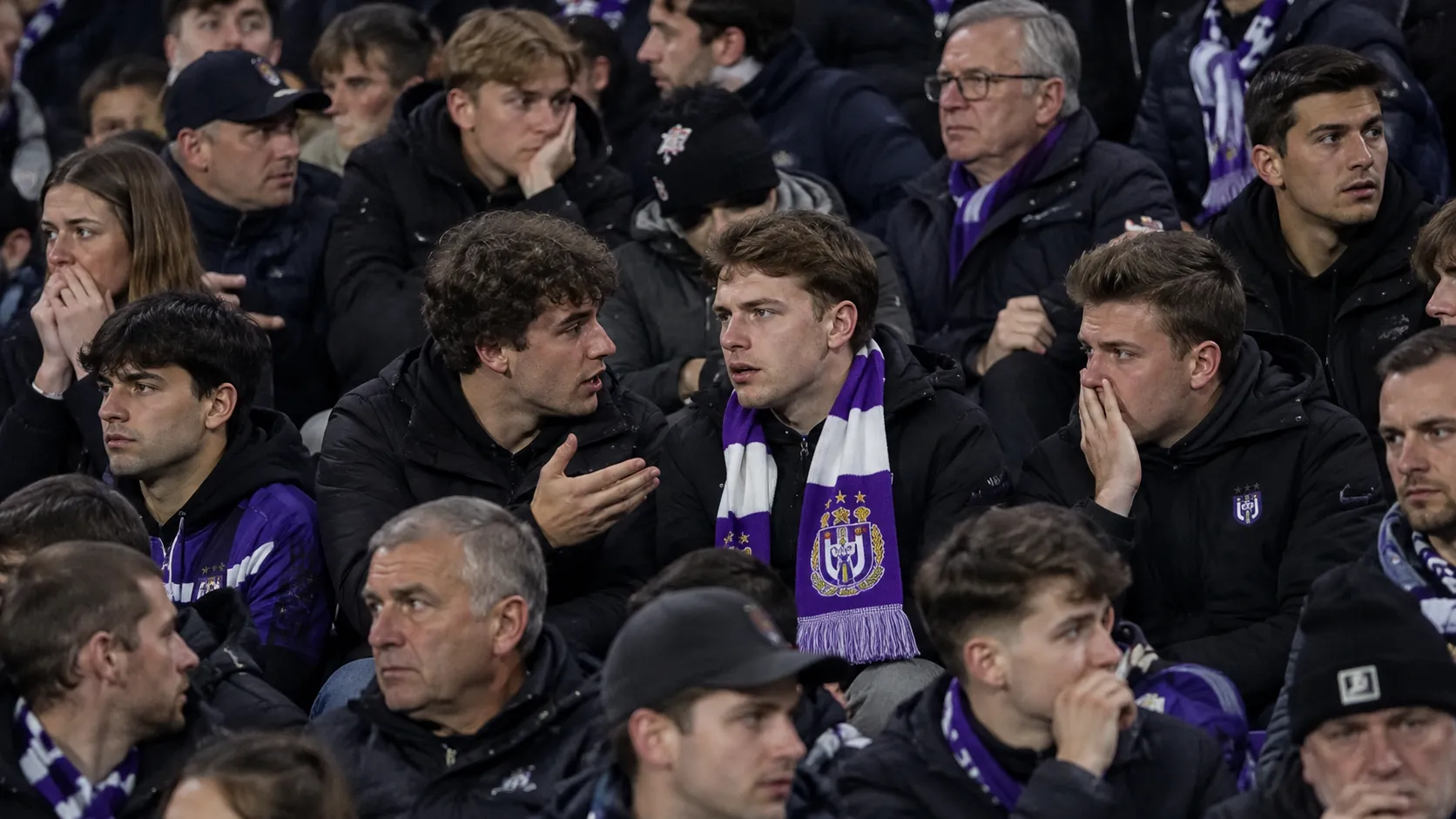 Een groep Anderlecht-supporters reageert in de tribune met een paars-witte sjaal zichtbaar tussen de fans.