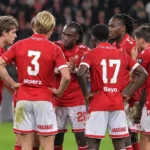 Een groep spelers van Standard Luik in rood-witte wedstrijdkleding op het veld.