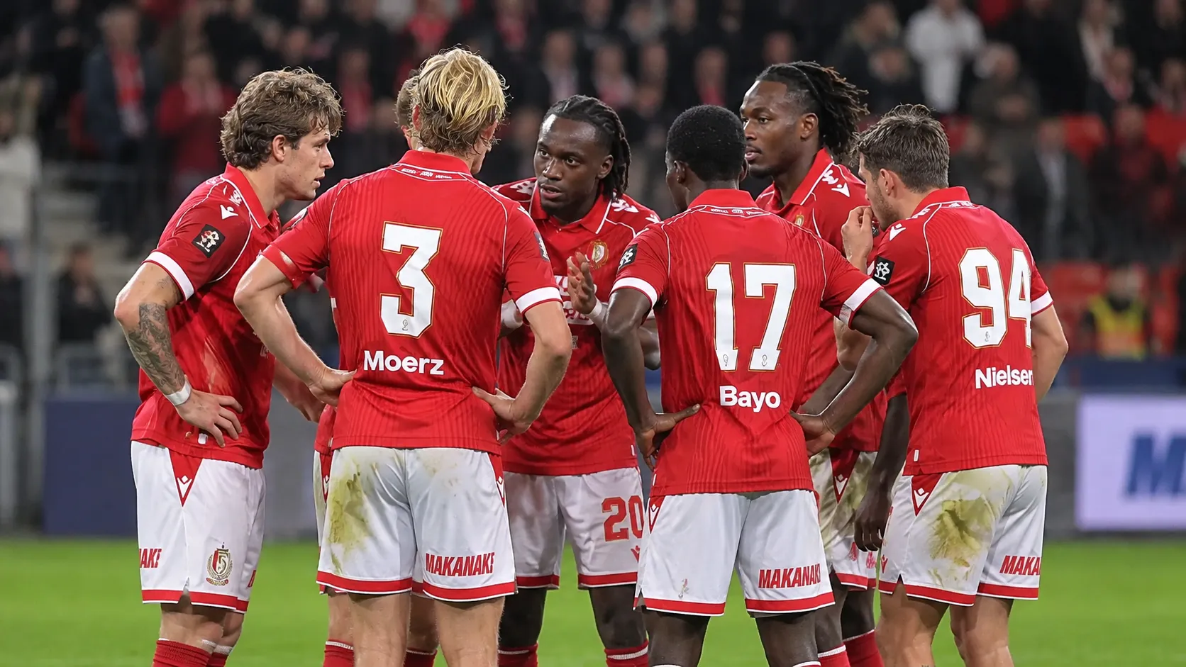 Een groep spelers van Standard Luik in rood-witte wedstrijdkleding op het veld.