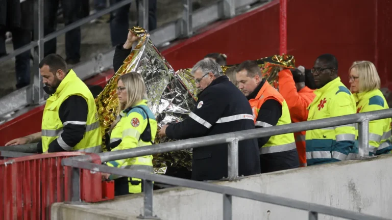 Een groep Standard-supporters applaudisseert in de tribune bij een medische interventie.