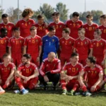 Belgische U17-selectie in rode shirts poseert samen op een voetbalveld.