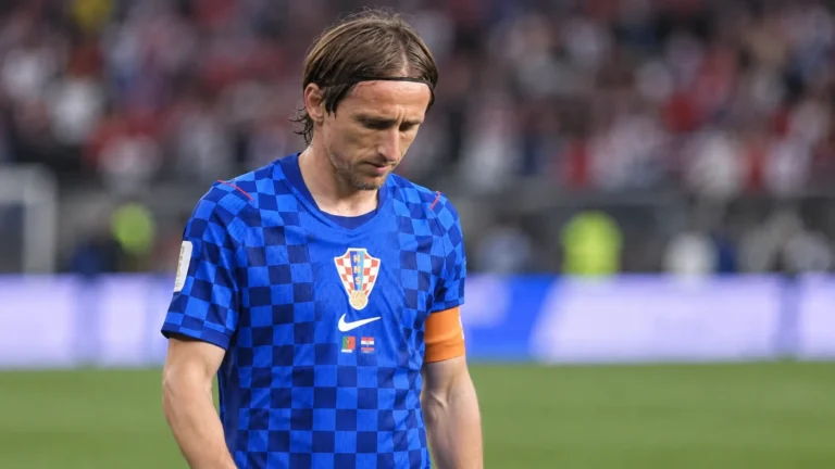 Een Kroatische speler in een blauw geruit nationaal shirt wandelt na de wedstrijd op het veld.