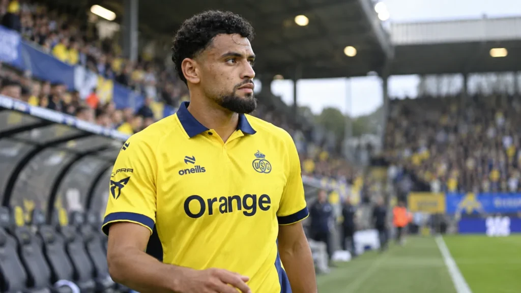 Adem Zorgane in het gele tenue van Union aan de rand van het veld.