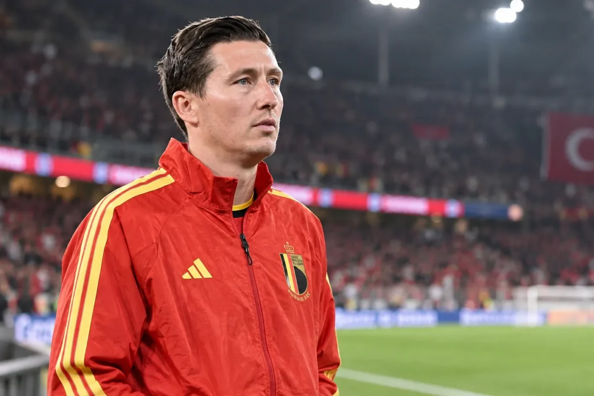 Hans Vanaken in een rode trainingsjas van België aan de zijlijn van een verlicht stadion.
