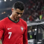 Cristiano Ronaldo in het rode tenue van Portugal aan de zijlijn van een stadion.