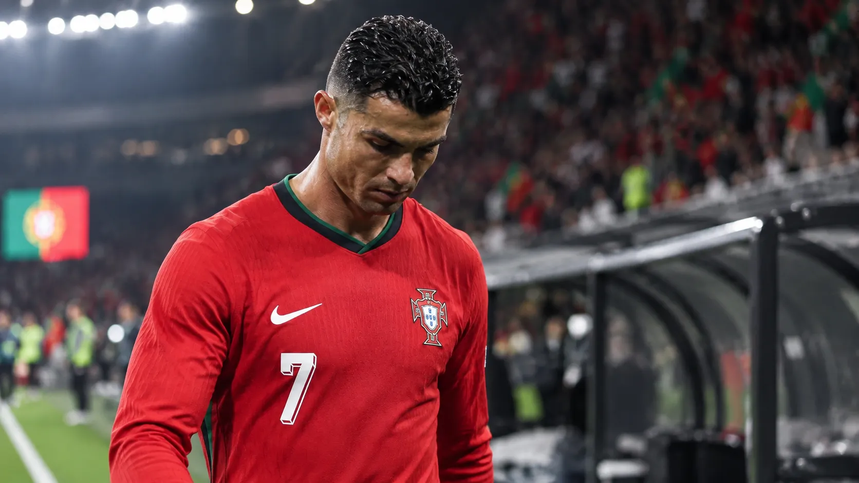 Cristiano Ronaldo in het rode tenue van Portugal aan de zijlijn van een stadion.
