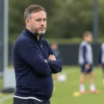 Michael Beale kijkt vanaf de zijlijn naar een voetbalveld.