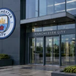 Lege ingang van een administratief gebouw van Manchester City met een vast clubembleem aan de gevel.
