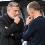 Twee leden van de Kroatische technische staf in gesprek op de bank van het stadion.