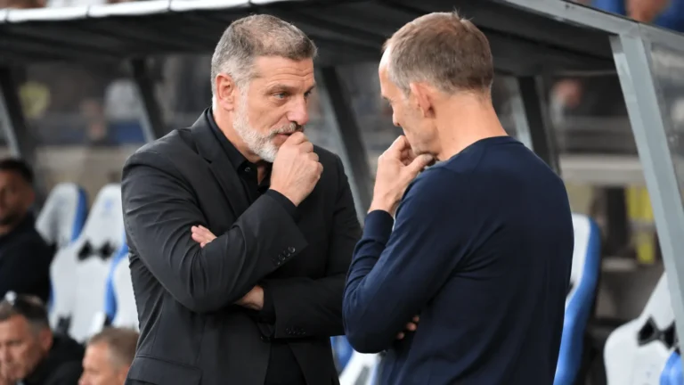 Twee leden van de Kroatische technische staf in gesprek op de bank van het stadion.