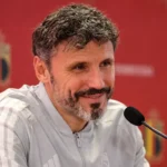 Een bondscoach van de Belgische nationale ploeg tijdens een persconferentie met microfoon.