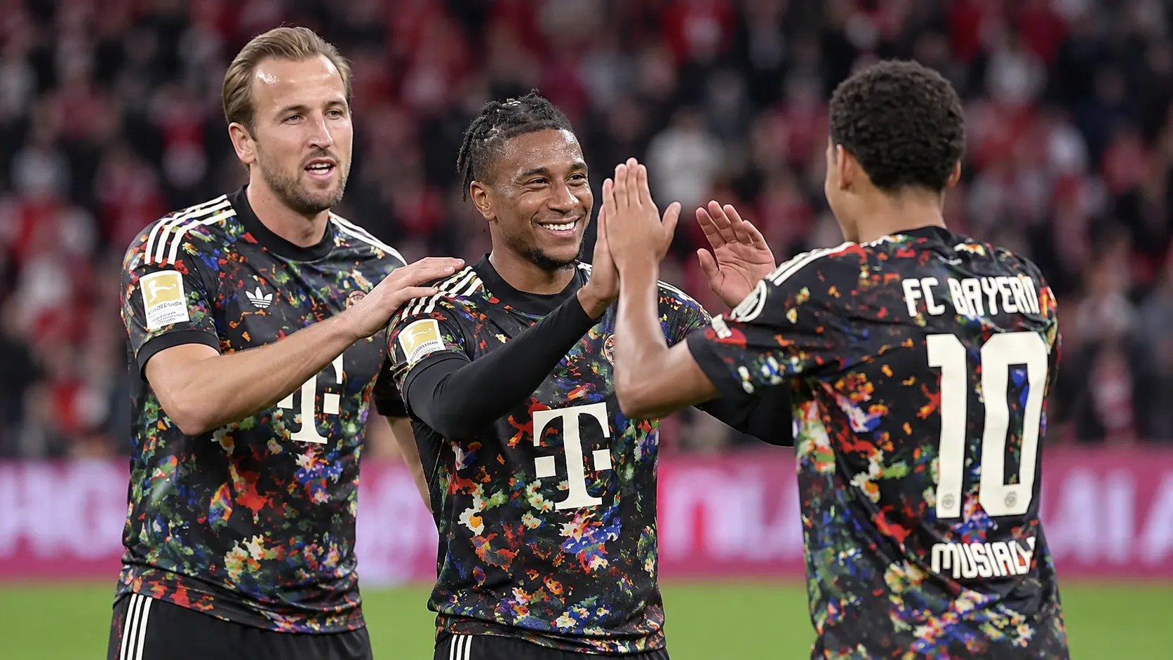 Drie voetballers in donkere shirts begroeten elkaar tijdens een wedstrijd.