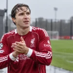 Federico Chiesa in Liverpool-tenue naast een nat trainingsveld.