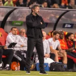 Een coach van de Belgische nationale ploeg observeert geconcentreerd vanuit de technische zone.