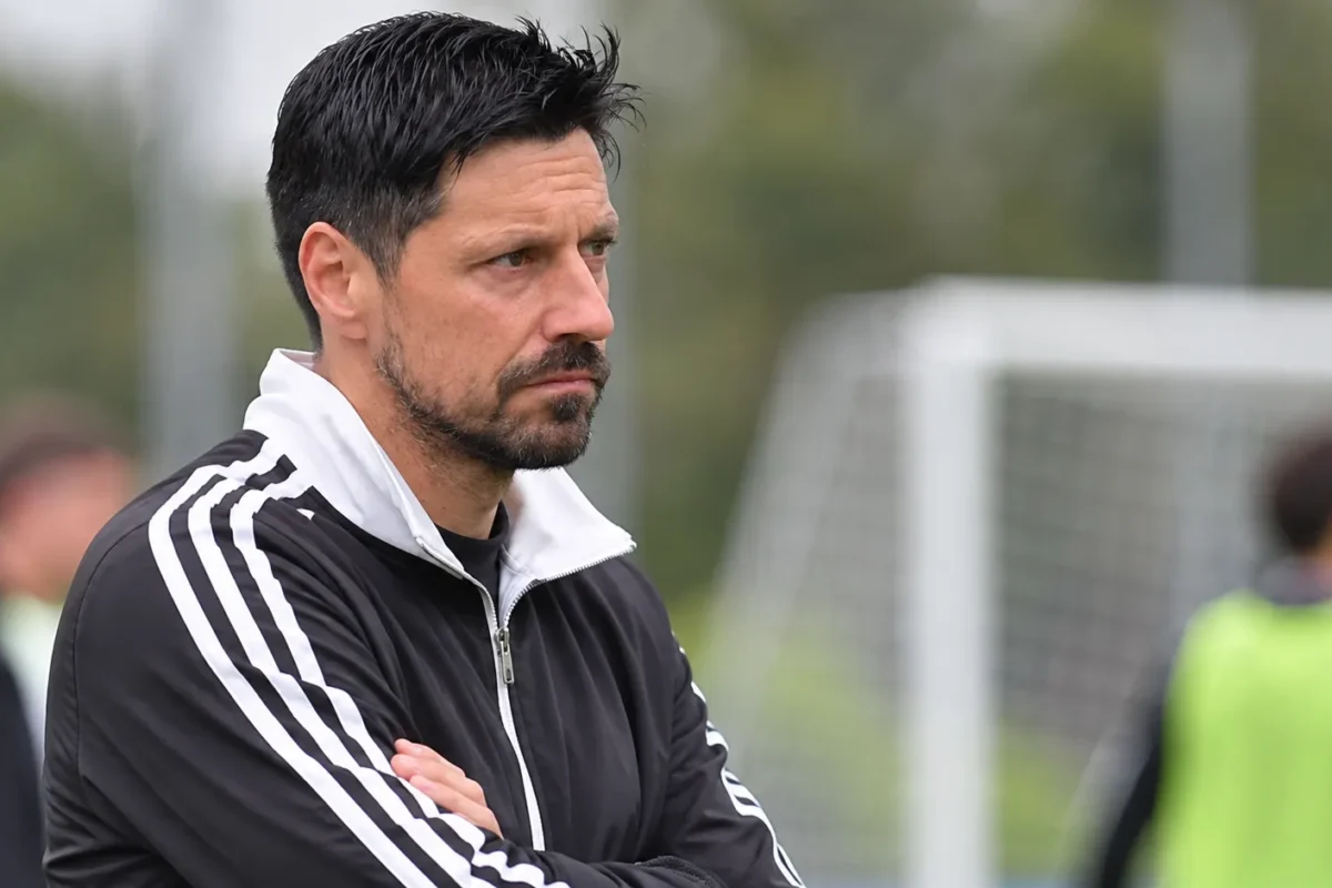 Een lid van de technische staf observeert een oefensessie op het trainingsveld.