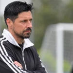 Een lid van de technische staf observeert een oefensessie op het trainingsveld.