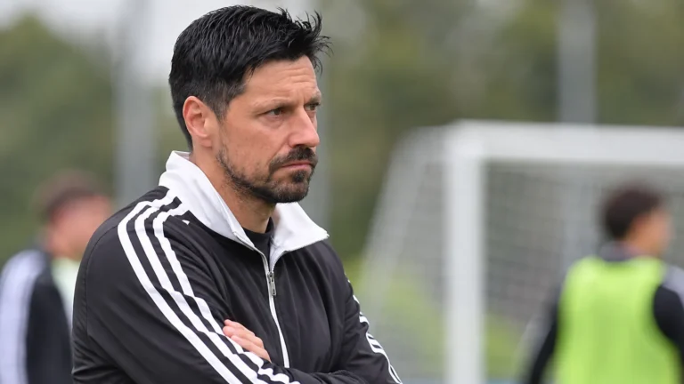 Een lid van de technische staf observeert een oefensessie op het trainingsveld.