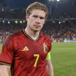 Kevin De Bruyne in het rode tenue van de Rode Duivels op het veld van een internationaal stadion.