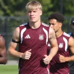 Een groep spelers in bordeaux trainingskleding tijdens een oefensessie.