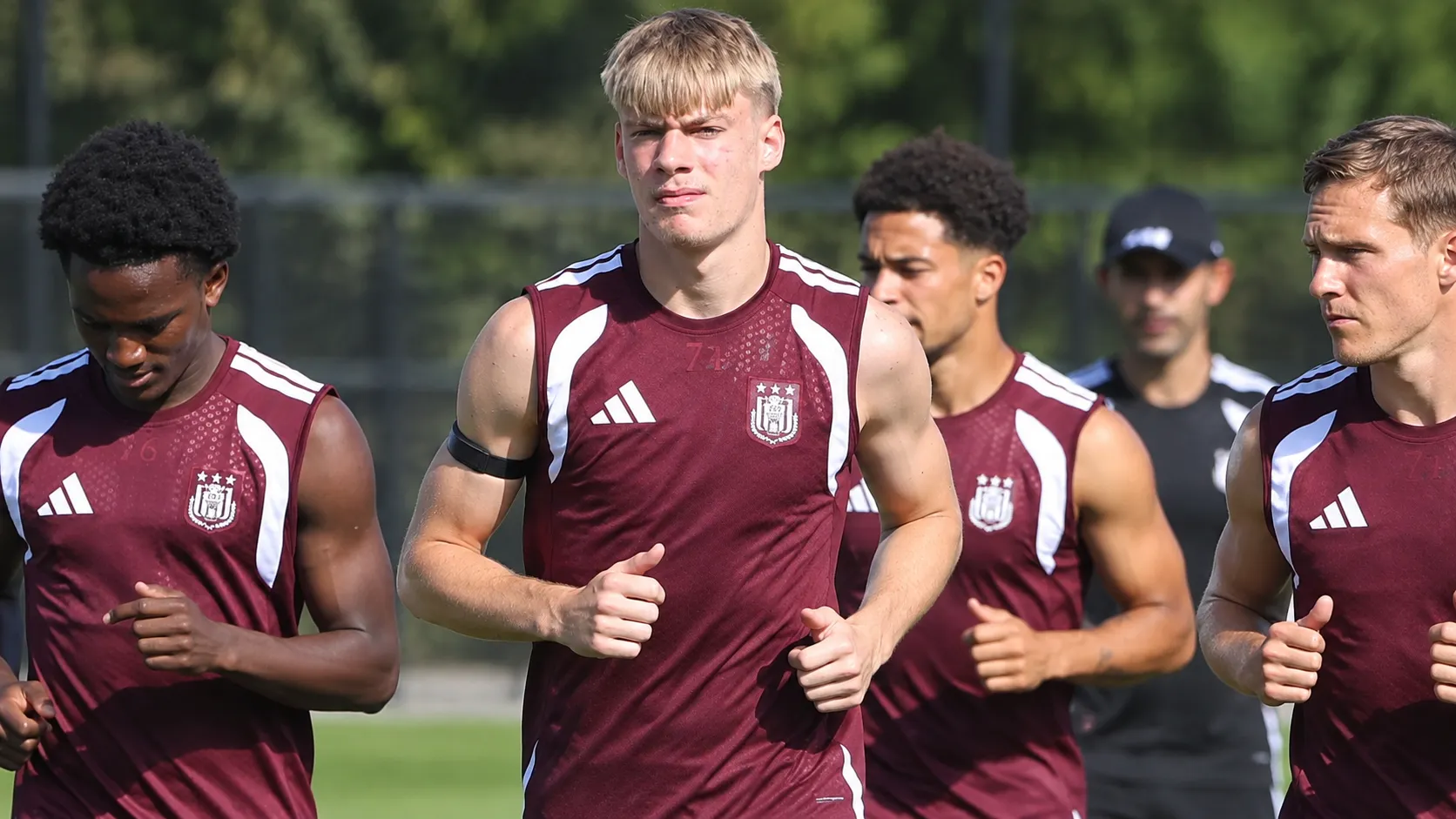 Een groep spelers in bordeaux trainingskleding tijdens een oefensessie.