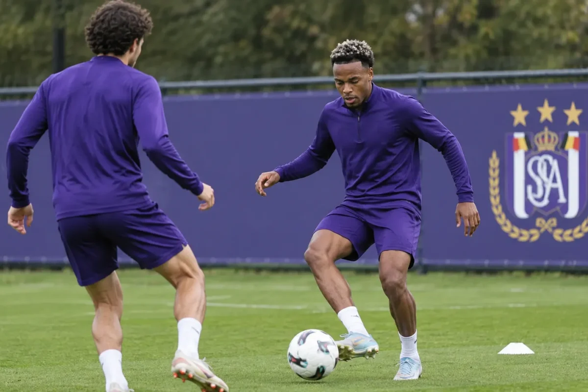 Twee Anderlecht-verdedigers trainen samen op een oefenveld naast een clubbord.