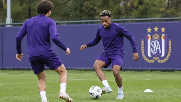 Twee Anderlecht-verdedigers trainen samen op een oefenveld naast een clubbord.