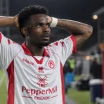 Een KV Kortrijk-speler in een wit-rood shirt reageert ontgoocheld op het veld.