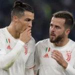 Twee Juventus-spelers in witte wedstrijdshirts communiceren tijdens een historische wedstrijd.