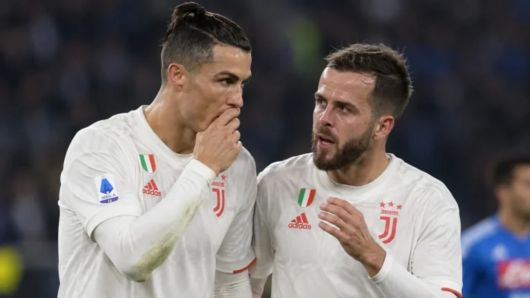 Twee Juventus-spelers in witte wedstrijdshirts communiceren tijdens een historische wedstrijd.