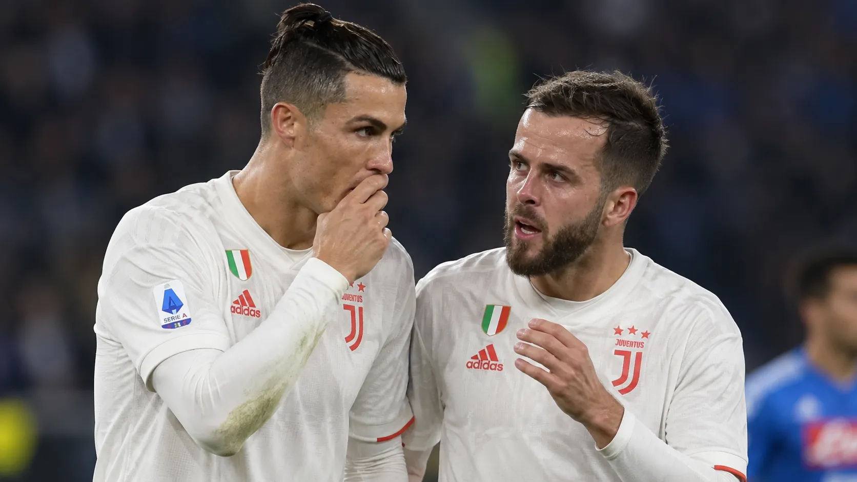 Twee Juventus-spelers in witte wedstrijdshirts communiceren tijdens een historische wedstrijd.
