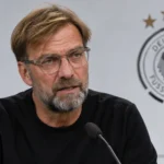 Jürgen Klopp spreekt in een interviewzone met een Duits nationaal ploegembleem op de achtergrond.