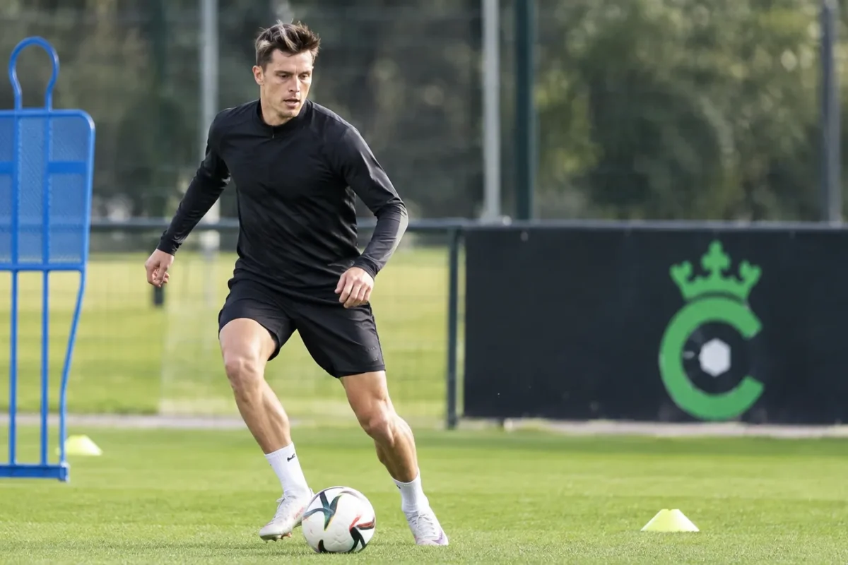 Hannes Van Der Bruggen op het trainingsveld van Cercle Brugge, met een clubbord op de achtergrond.