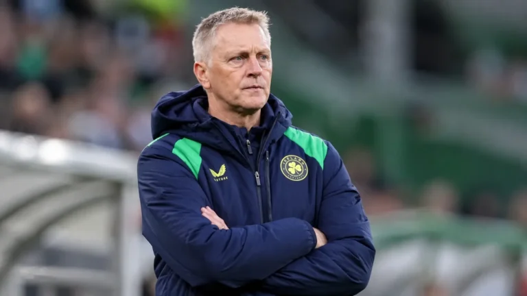Heimir Hallgrímsson in Ierse trainingsjas aan de zijlijn van een voetbalveld.