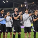 Een groep Anderlecht-spelers applaudisseert na een wedstrijd voor de supporters.