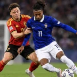 Een Belgische en een Franse speler vechten om de bal tijdens een interlandduel.