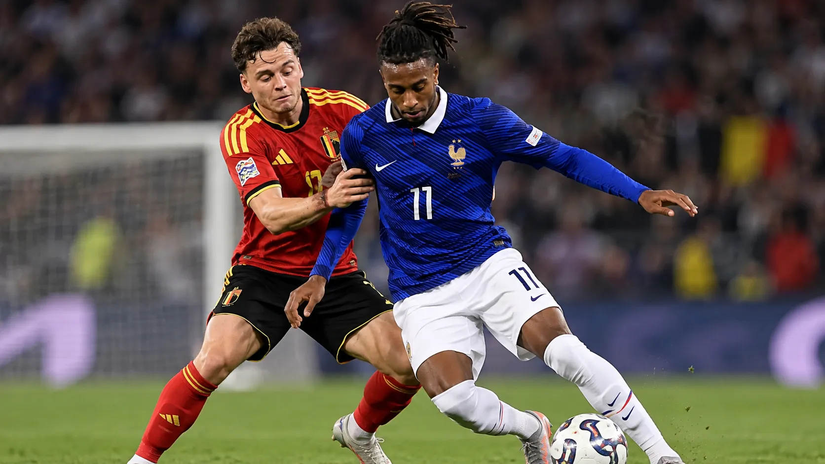 Een Belgische en een Franse speler vechten om de bal tijdens een interlandduel.
