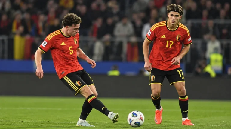 Twee Belgische internationals in rood wedstrijdtenue tijdens een passmoment op het veld.