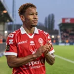 Shandre Campbell in het rode shirt van KV Kortrijk aan de rand van een voetbalveld.